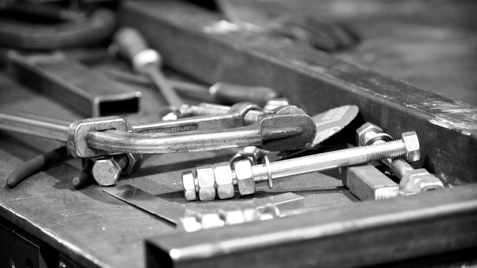 A steel fabricator's bench with clamps, bolts and a rule laid out on the work